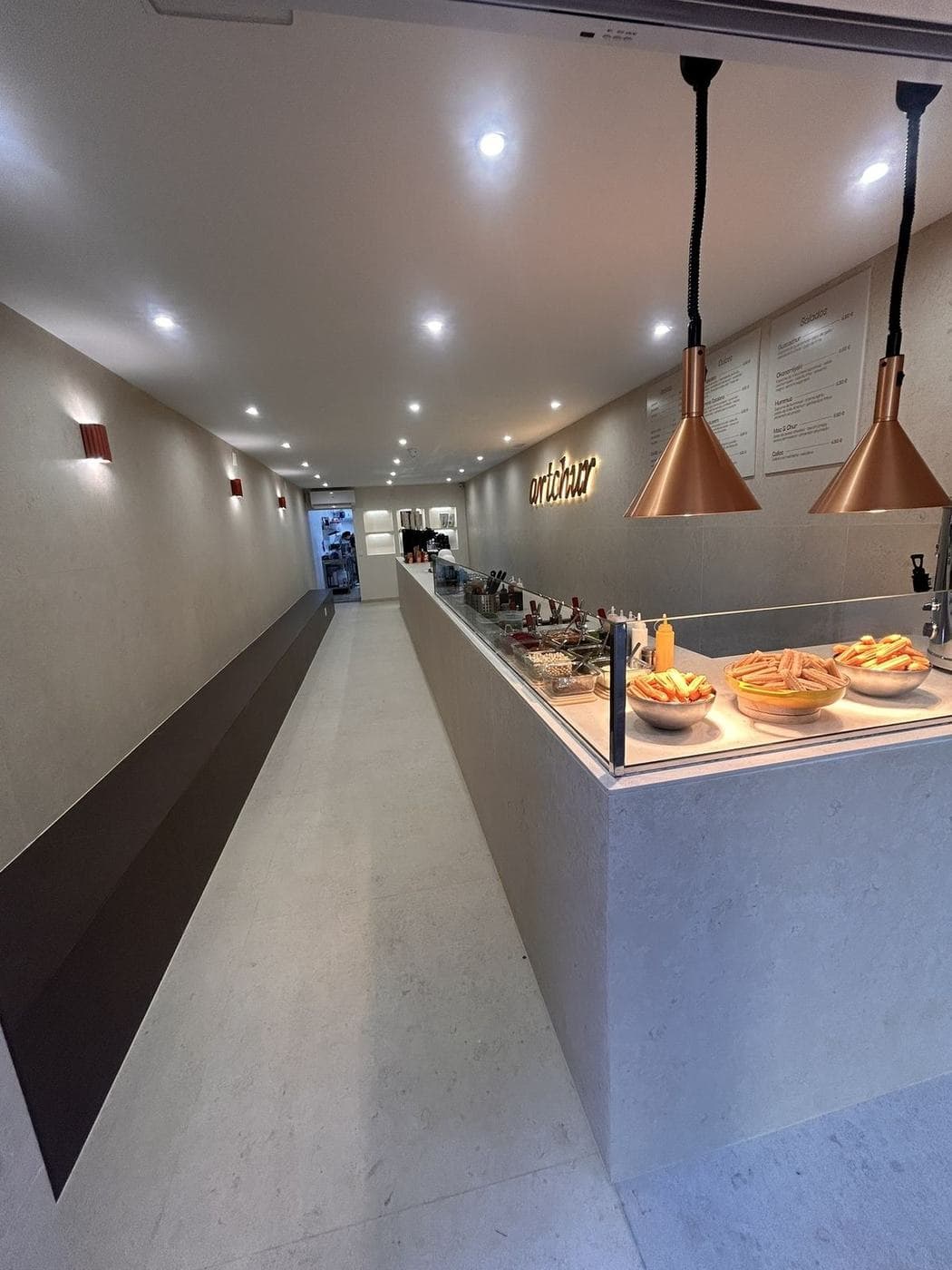 La churrería terminada: barra corrida de piedra clara y lámparas cobrizas