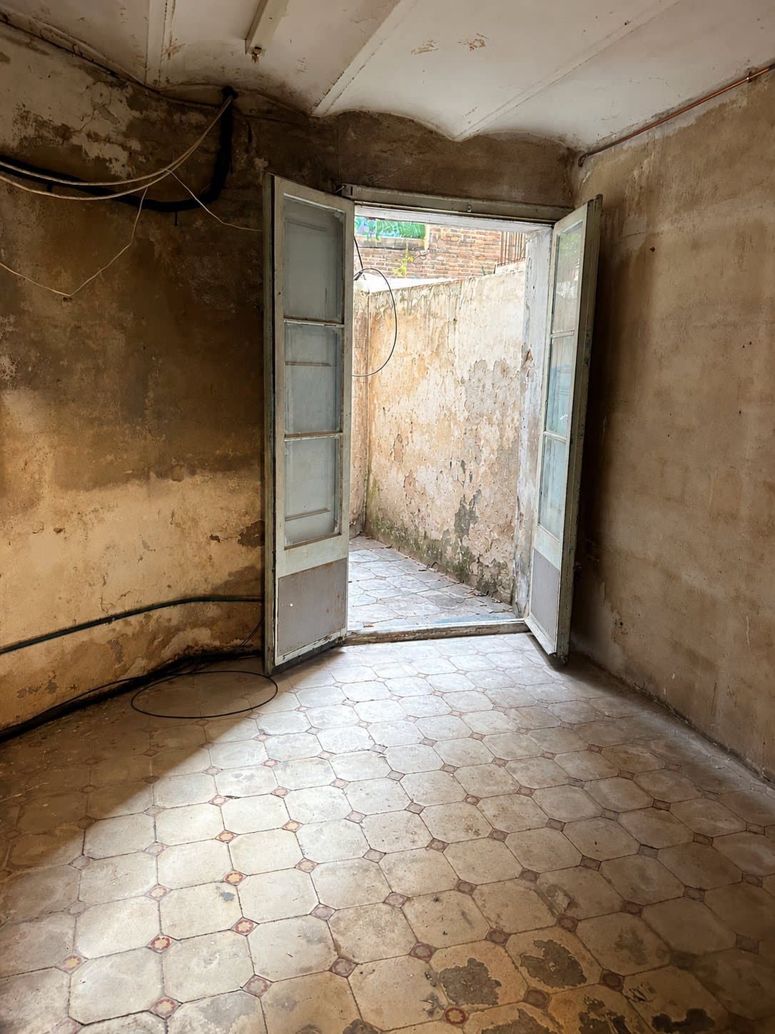 Fondo del local antes de la obra, con pavimento hidráulico antiguo y paredes desconchadas