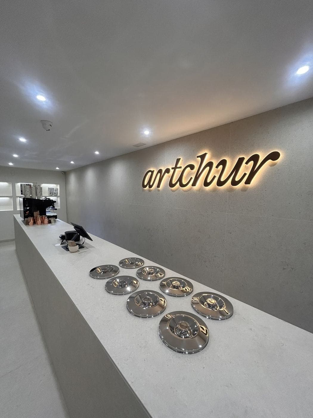 Barra de piedra clara y rótulo retroiluminado de Artchur en la pared del fondo