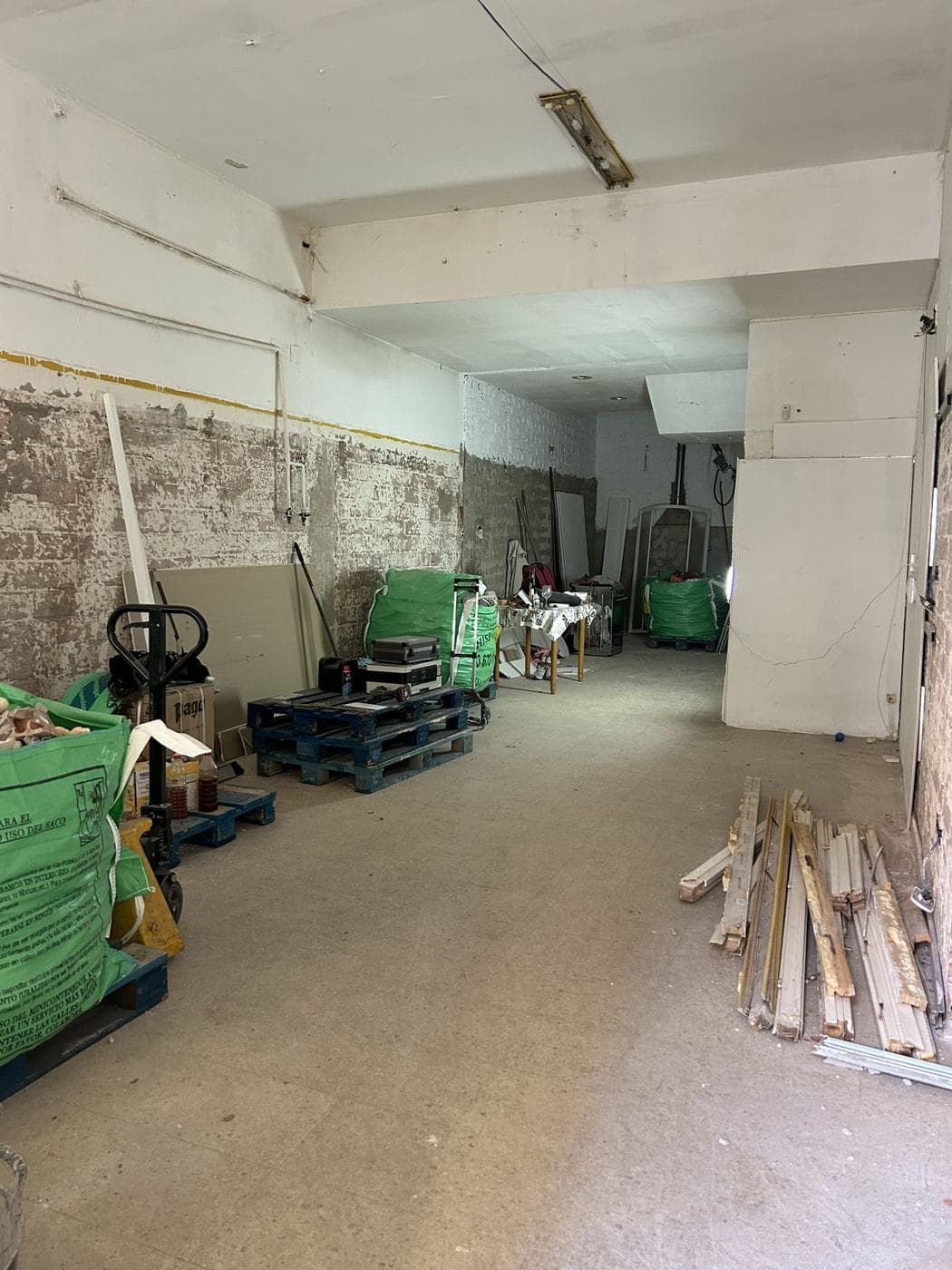 Interior del local durante la demolición, con sacas de escombro y placas de yeso