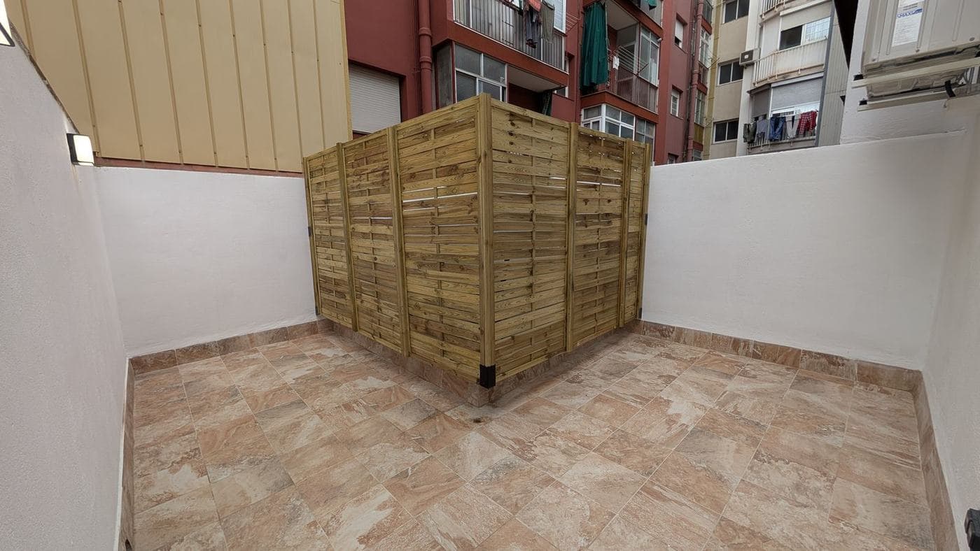 Patio después: pavimento nuevo, paneles de madera y aplique de pared