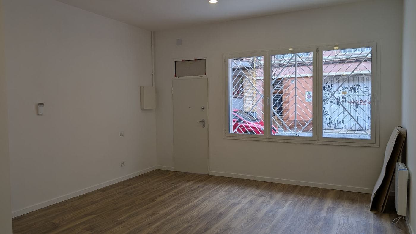 Salón de una vivienda en planta baja con ventana protegida por celosía, antiguo local comercial