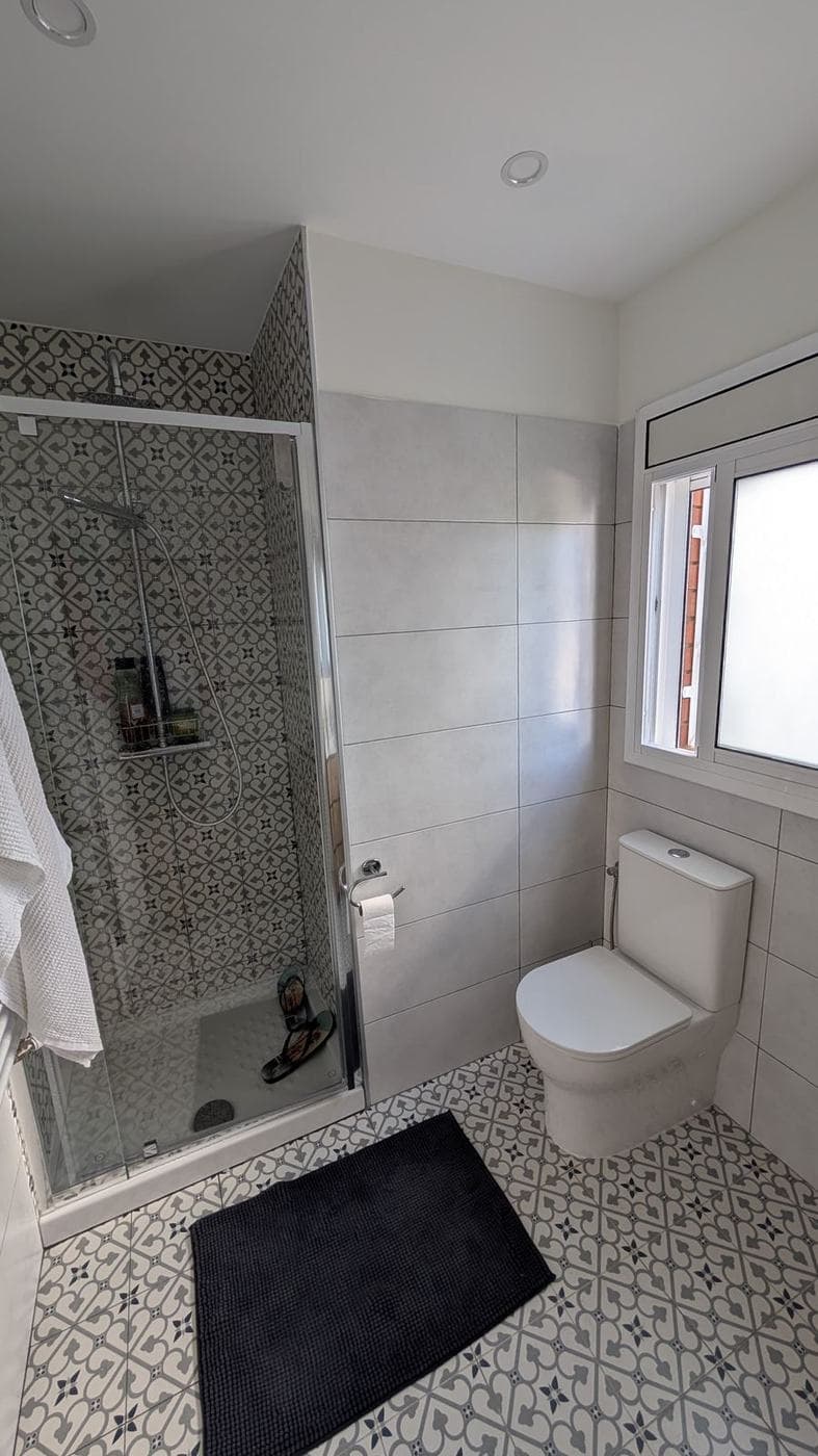 Baño con ducha de mampara, suelo hidráulico y radiador toallero