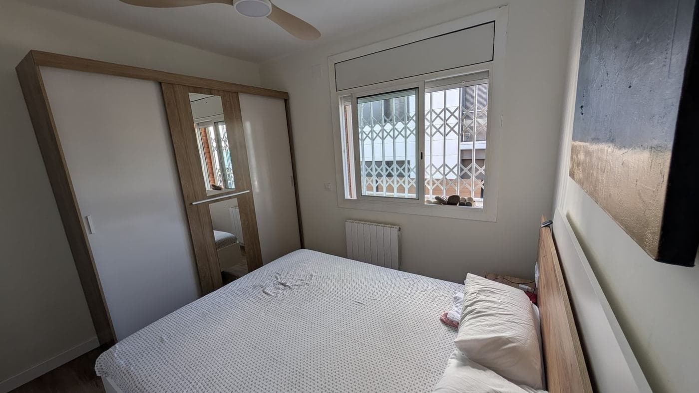 Dormitorio con armario de madera clara y ventana a la calle