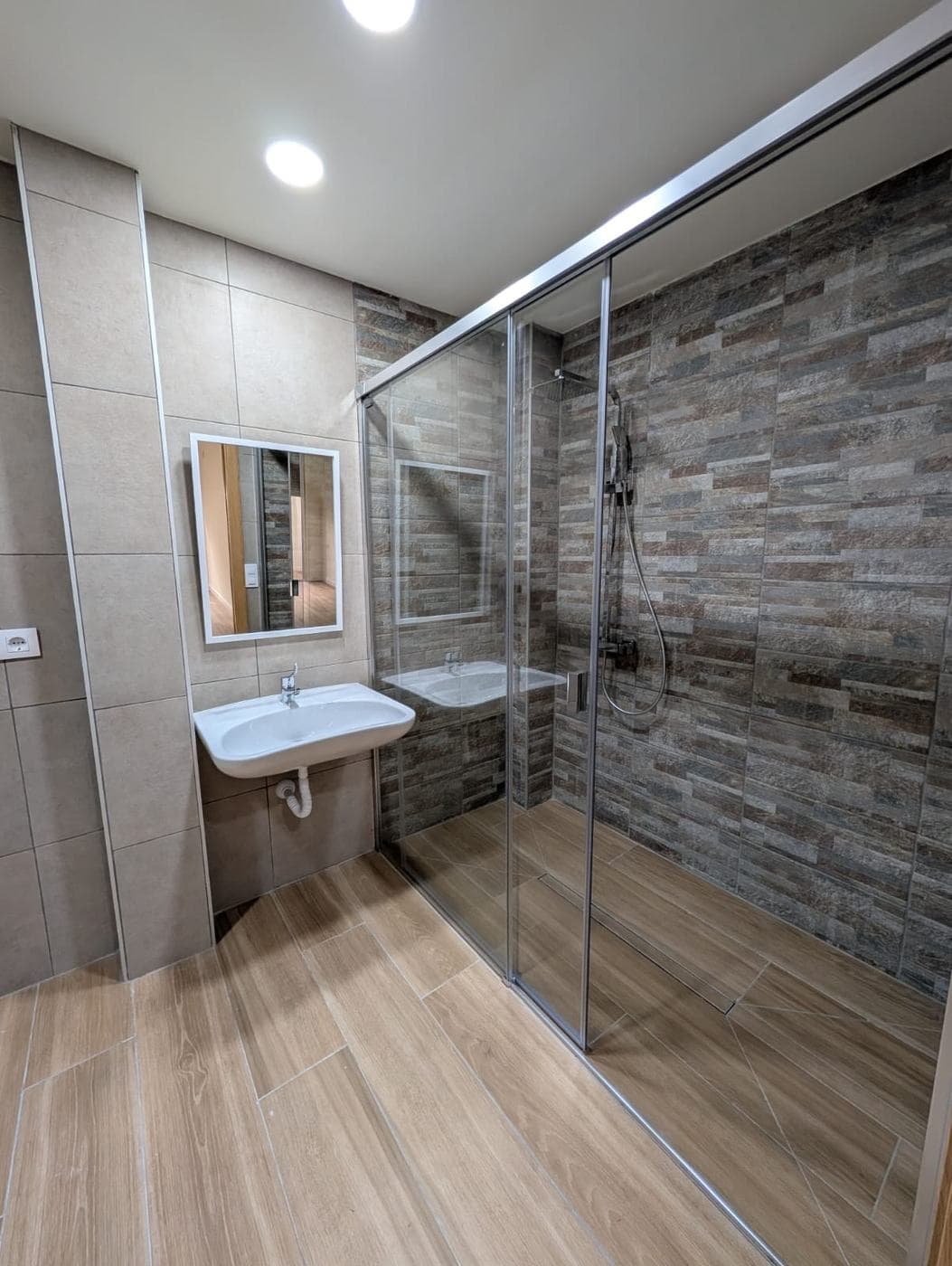 Baño con lavabo suspendido sin mueble inferior y ducha con mampara corredera