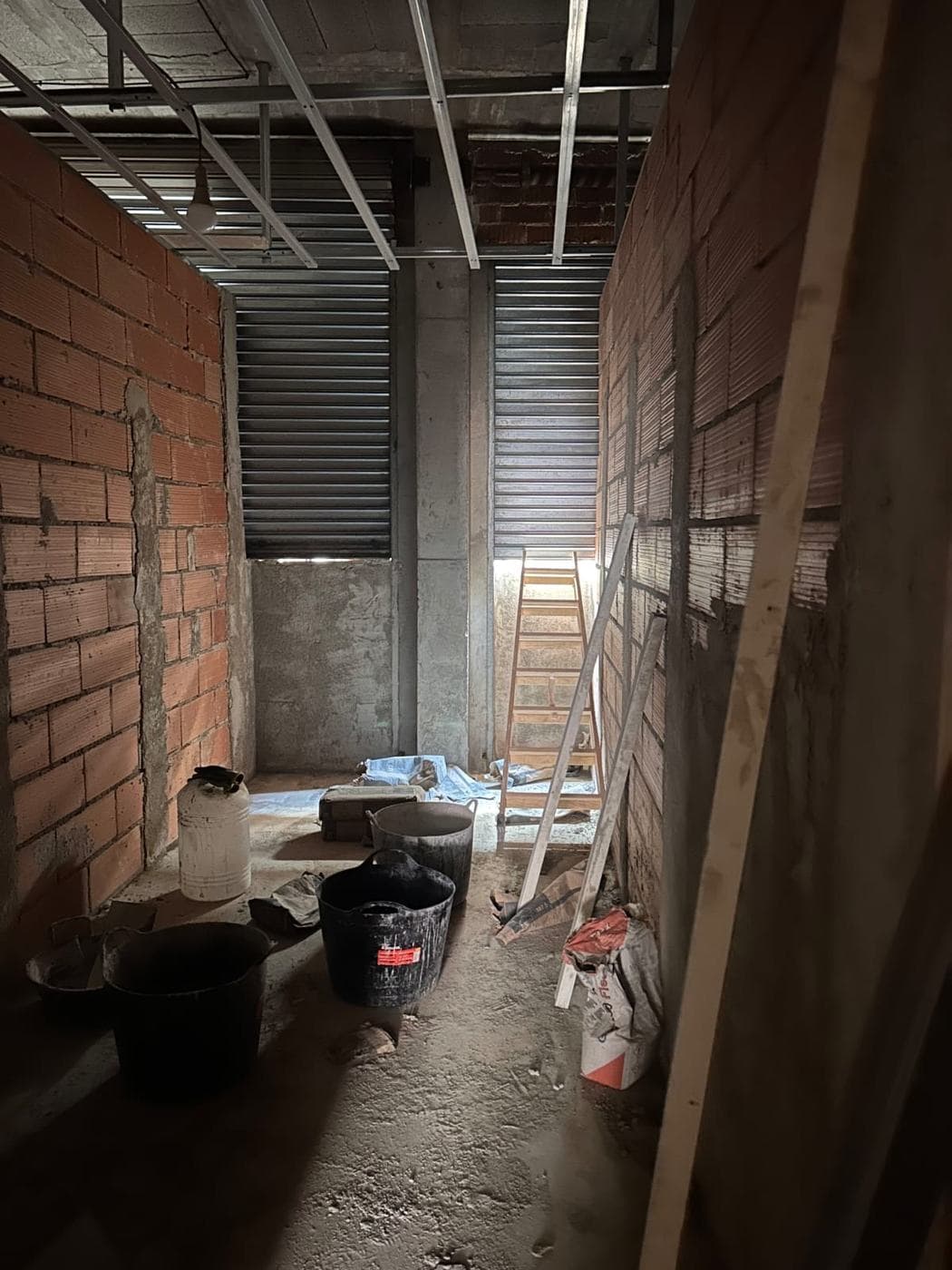 Muros de ladrillo y persiana metálica del local antes de la reforma