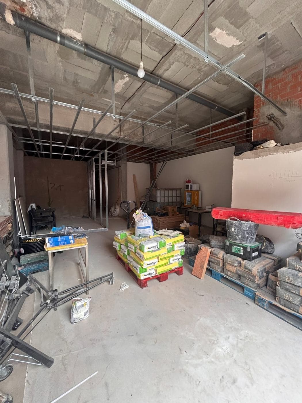 Local en obra con perfilería en el techo y palés de material