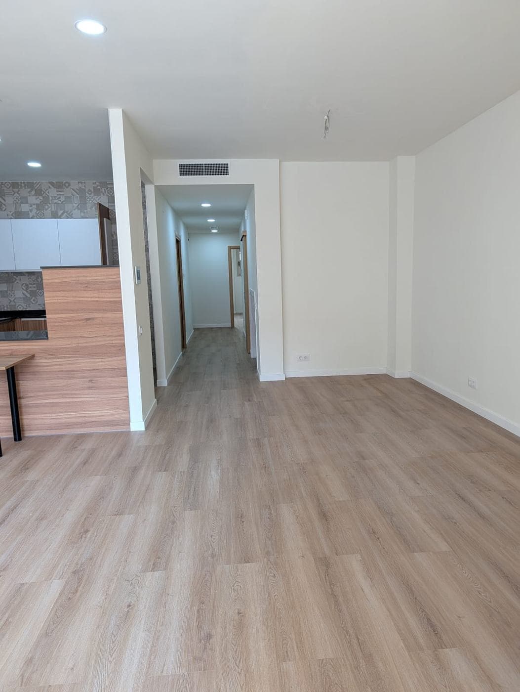 Salón terminado, con la cocina abierta a la izquierda y el pasillo al fondo