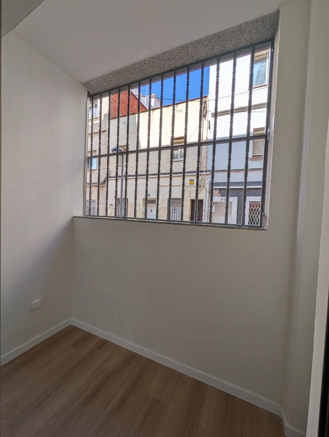 Ventana alta a la calle protegida con reja metálica