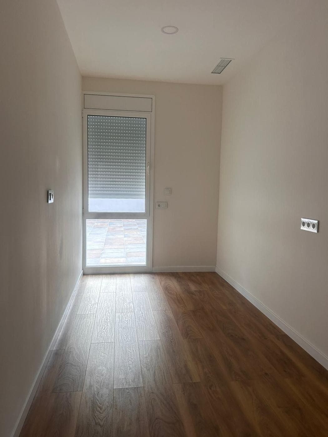 Dormitorio con ventana a la terraza y suelo de madera