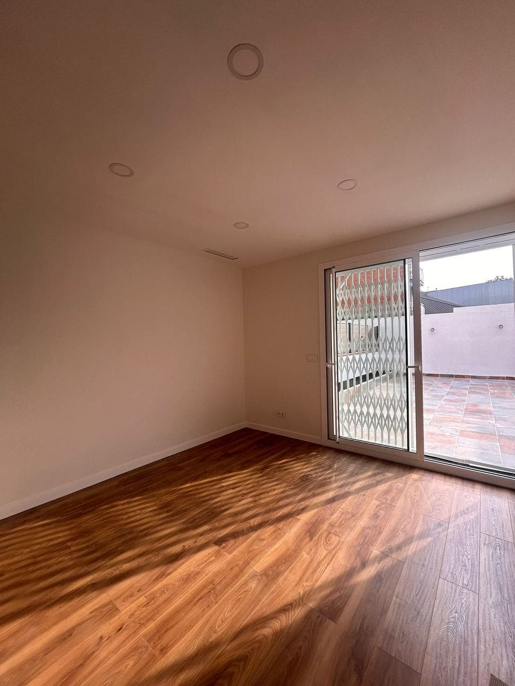Habitación con suelo de madera y puerta acristalada a la terraza