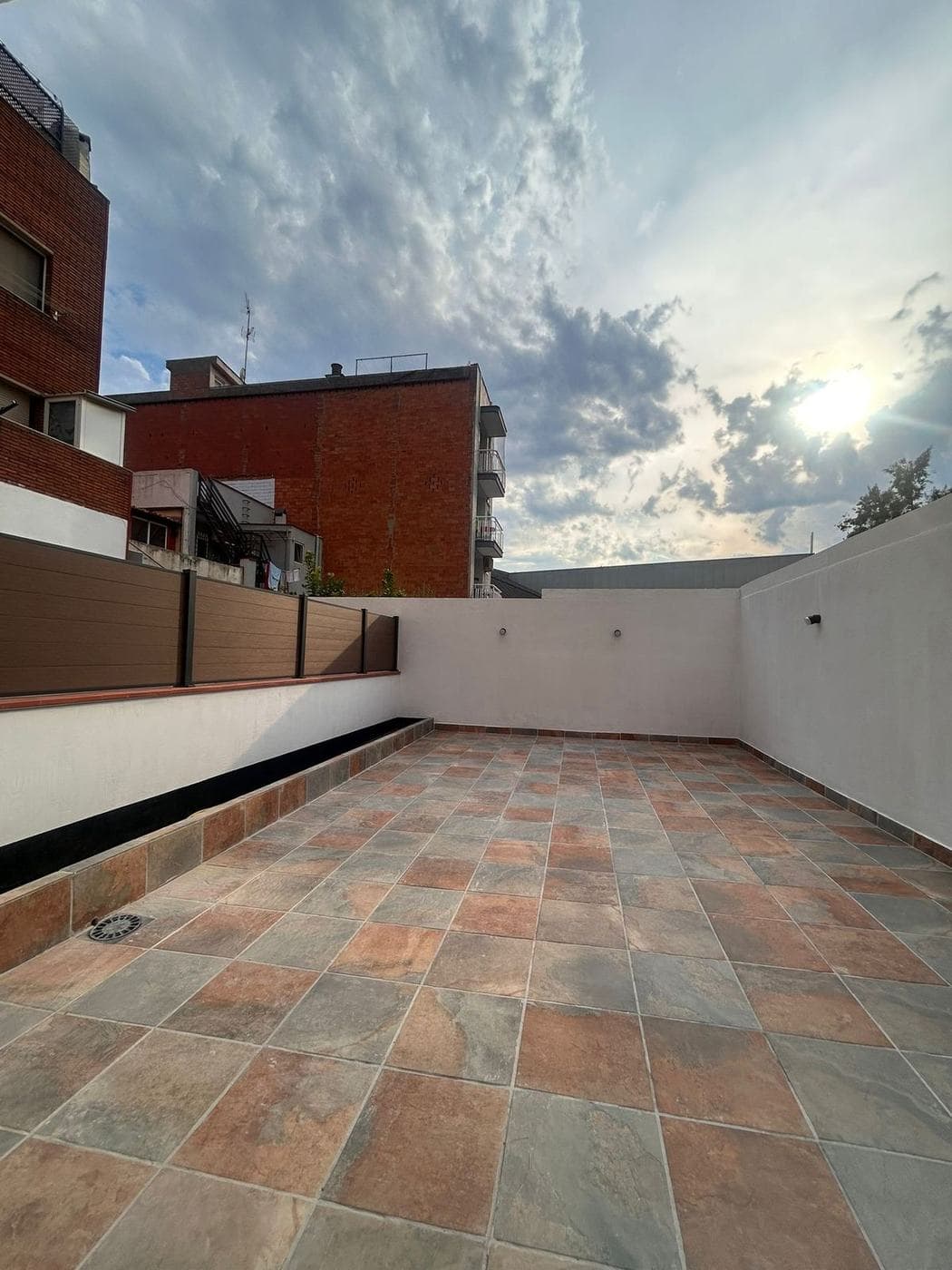 Terraza pavimentada con gres al atardecer, con frente de lamas y apliques encendidos